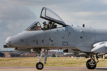 A10 jet in grey colour scheme with cockpit open taxis past the camera. pilot wearing helmet and oxygen mask. 