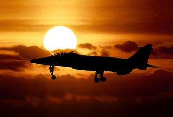 RAF Jaguar strike attack fighter at sunset silhouetted against an orange sky - obrazy, fototapety, plakaty