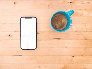 Mockup of smartphone on wooden table - top view - white blank screen - breakfast scene with cup of...