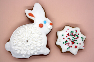 Gingerbread in the shape of a bunny covered with icing on a pink background.