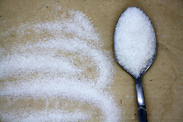 Sugar poured into a spoon on craft paper.
