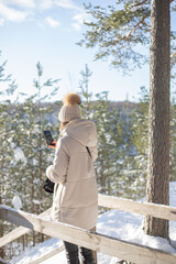 Fototapeta premium Young woman take a photo with mobile phone in snowy forest.