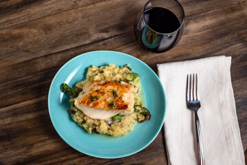Chilean sea bass over a bed of mushroom asparagus risotto and a glass of red wine overhead view