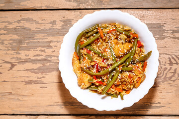 Vegetables with chicken fillet in pan-Asian sauce with sesame seeds on a wooden table in a plate kopy place.