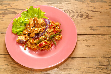 Vegetables with chicken meat in pan-Asian sauce with sesame seeds on lettuce leaves on a wooden table in a plate copy the place.