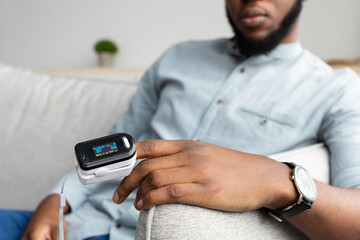 Black Man With Pulse Oximeter Measuring Oxygen Saturation At Home