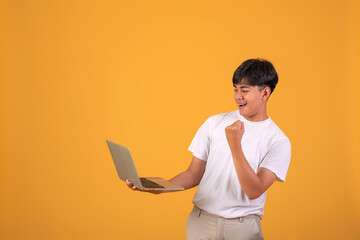 Asian man holding looking a laptop on orange background.