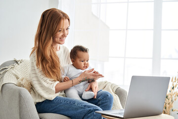 Happy young single caucasian mother holding cute small african mixed race infant baby girl, child...