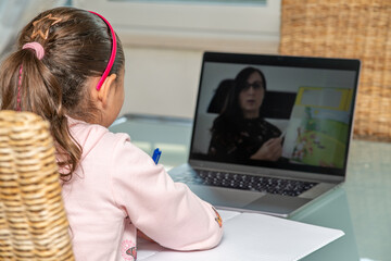 Home schooling concept. Young girl following school lesson from her laptop in pandemic time