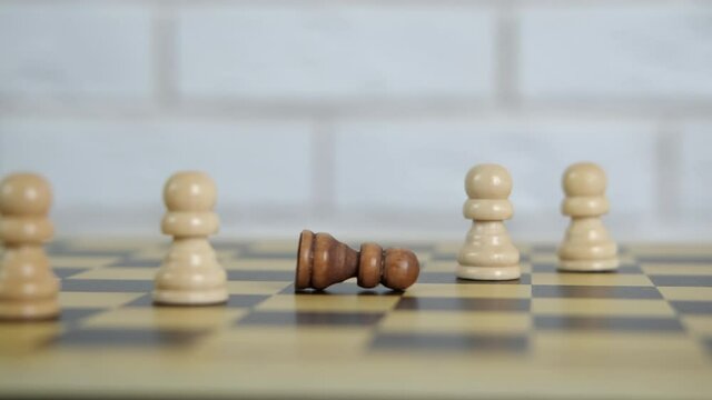 The Concept Of Racial Inequality. The Black Chess Piece Is Lying On The Chessboard And The White Pieces Are Standing.