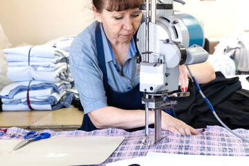 A woman with a cutting machine at a sewing industrial workplace. Fabric cutter.