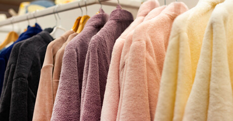 Photo of different colored bathrobes hanging on shopping rack.
