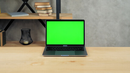 Modern laptop computer display with mock up chroma key green screen standing on table working...