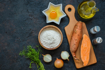 Prepared ingredients for sweet potato or carrot fritters on a dark concrete background.