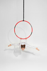 graceful little child girl gymnast in white sportwear doing twine on an aerial hoop © Rychko Yevhen