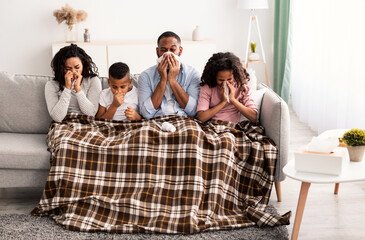 Sick black family blowing noses with napkins together