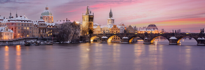 
panorama of snowy charles bridge at sunset in winter and pink colored sky with light in prague in czech republic - obrazy, fototapety, plakaty