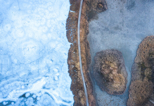 Aerial drone fly air shot, view on ice lake frozen winter top down road moody mood grey blue Saxony germany Guttau