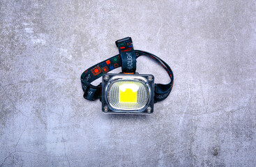 Head torch flashlight on gray concrete background