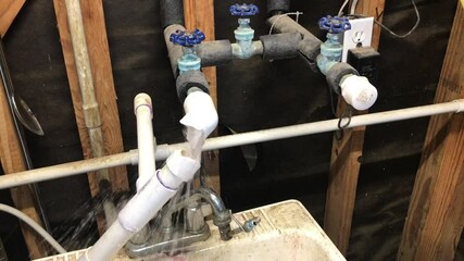 Water pouring from frozen burst water pipe after winter freeze