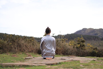 Young man in Tai Chi suit meditating on the mountain