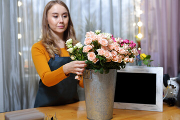 florist woman chooses roses for bouquet. Flowers bunch, set for home. Fresh cut flowers for decoration home. European floral shop. Delivery fresh cut flower.
