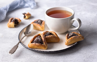 Homemade hamantashen cookies (Haman's ears) with poppy seeds and apples on a light gray background. Traditional pastries for Purim, Jewish carnival