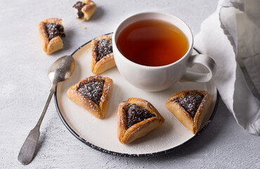 Homemade hamantashen cookies (Haman's ears) with poppy seeds and apples on a light gray background. Traditional pastries for Purim, Jewish carnival