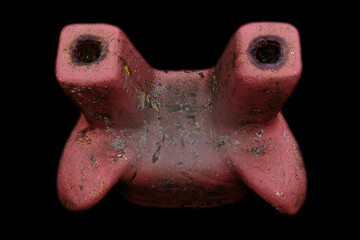 Large red metal cleat from old dock with black background.