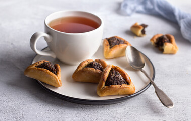 Homemade hamantashen cookies (Haman's ears) with poppy seeds and apples on a light gray background. Traditional pastries for Purim, Jewish carnival