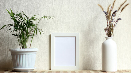 Poster with copy space. Mockup of a wooden frame with home plant tropical palm tree, with vase with dried flowers. White, minimalism. copy space. Mock up design.