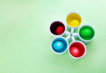 Close up of easter eggs dye process against green background. Image with copy space