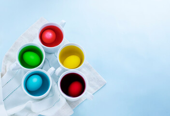 Close up of easter eggs dye process against light blue background. Image with copy space