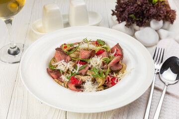 Pasta with veal on a white wooden table
