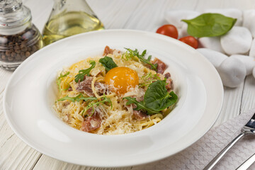 Pasta with egg and parmesan on a white wooden table 
