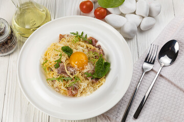 Pasta with egg and parmesan on a white wooden table 
