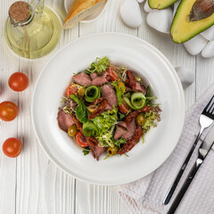 Pasta with herbs and veal on a white wooden table
