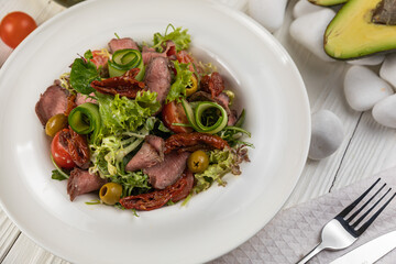 Pasta with herbs and veal on a white wooden table
