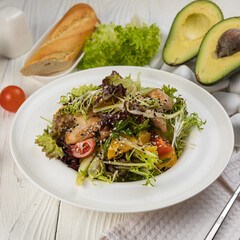Salad with herbs and meat on a white wooden table
