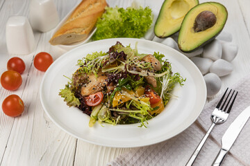 Salad with herbs and meat on a white wooden table

