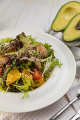 Salad with herbs and meat on a white wooden table
