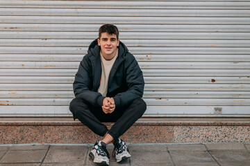 casual young man sitting on the city street