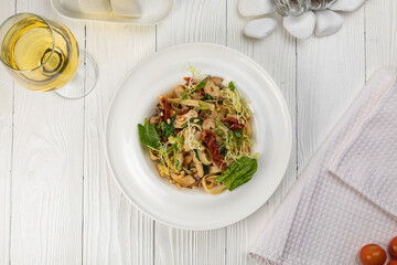 Pasta with herbs and mushrooms on a white wooden table
