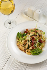 Pasta with herbs and mushrooms on a white wooden table
