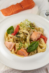 Pasta with herbs and salmon on a white wooden table
