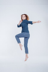 Funny european teenager curly hair girl dancing in studio. Portrait of cheerful fashion jumping hipster girl