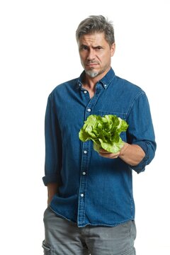 Casual older white man man holding green salad - healthy eating. Disappointed and misgiving.