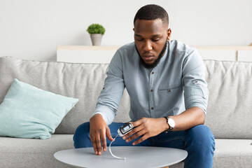 African Guy With Pulse-Oximeter Measuring Level Of Oxygen Saturation Indoor