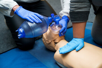 Medic in latex gloves using CPR technique on dummy in first aid class. Oxygen mask on medical doll....