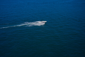 Obraz premium Top view of the boat. Top view of a white boat sailing in the blue sea. A boat with a motor on blue water. Aerial view luxury motor boat.